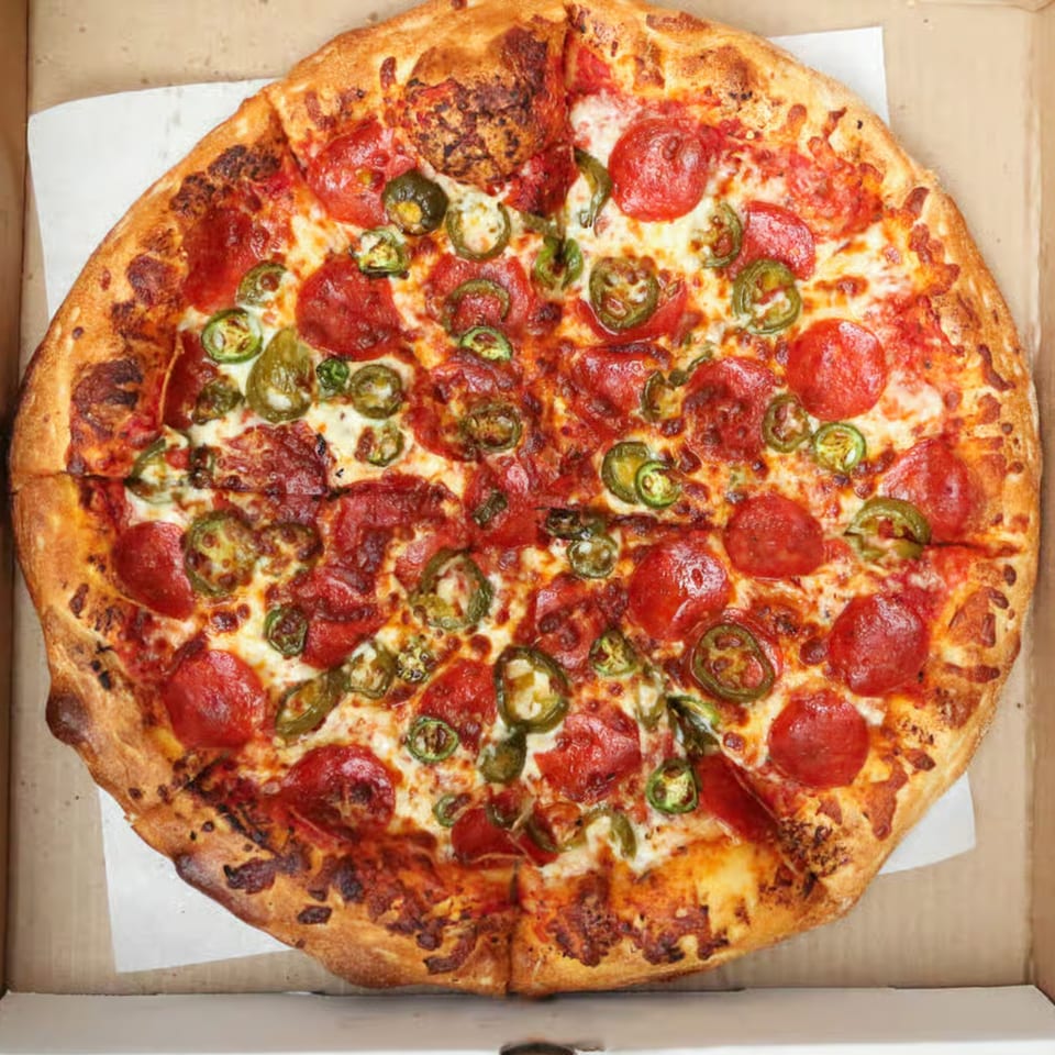 Mizan Pizza's pepperoni and jalapeño pizza, with a golden crust, in a cardboard box.