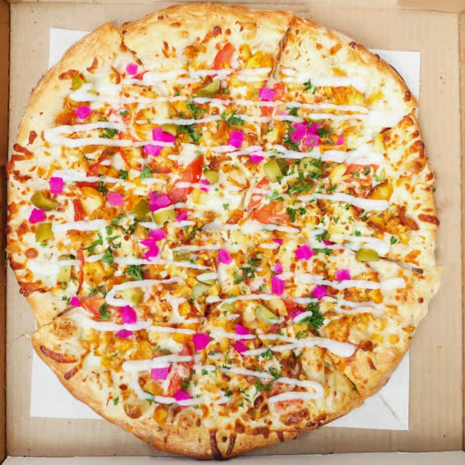 Mizan Pizza's chicken shawarma pizza, topped with white sauce, pickles, tomatoes, and parsley in a box.